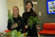 Foto von zwei Mitarbeiterinnen des Marienhofs in unserem UCB Büro in Monheim, mit frischem Gemüse in der Hand.